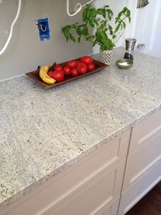 a tray with tomatoes and bananas on top of a kitchen counter next to a potted plant