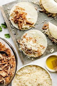 shredded meat and cheese on tortillas next to other ingredients