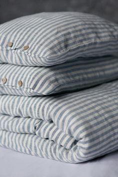 three blue and white striped pillows stacked on top of each other