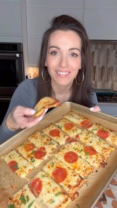 a woman is holding up a pizza in front of her face and smiling at the camera