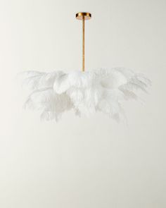 a white feather chandelier hanging from a gold ceiling fixture in an empty room