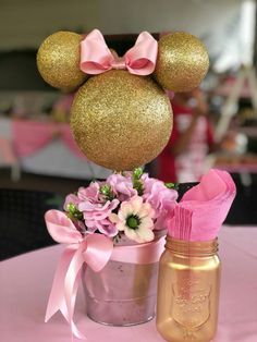 a pink and gold minnie mouse centerpiece next to a mason jar filled with flowers