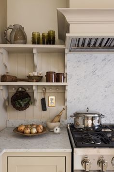 a stove top oven sitting inside of a kitchen next to a wooden shelf filled with pots and pans