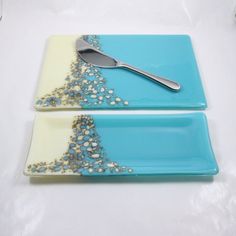 two blue and white plates with silver beaded designs on them, one has a spoon in the middle