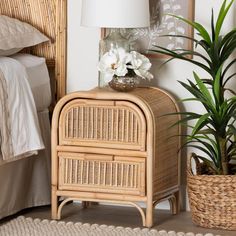 a wicker night stand next to a bed with white flowers on it and a lamp