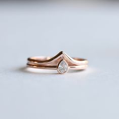 two gold wedding bands with a pear shaped diamond in the middle, set on top of each other