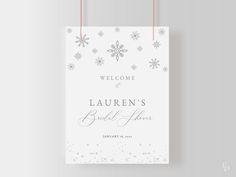 a welcome sign hanging from a string on a white wall with snowflakes in the background