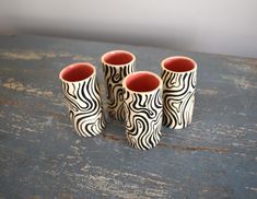 four black and white vases sitting on top of a wooden table