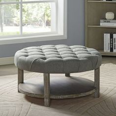 a grey ottoman sitting on top of a rug in a living room next to a window