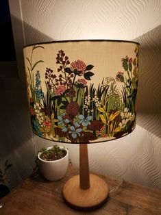 a lamp that is sitting on top of a table next to a potted plant