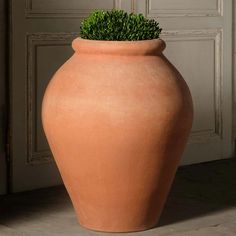 a large clay vase with a plant in it's center sitting on the floor