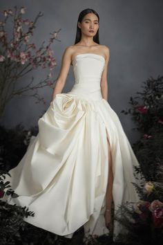 a woman in a white wedding dress standing next to flowers