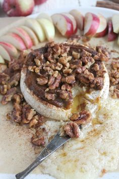 an apple pie with pecans and cinnamon on top sits on a plate next to sliced apples