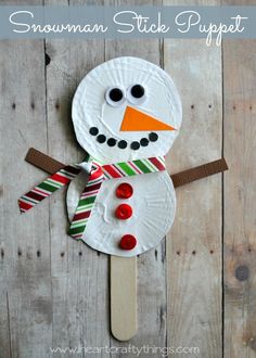 a paper plate snowman sitting on top of a wooden table