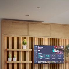 a flat screen tv sitting on top of a wooden shelf in front of a wall