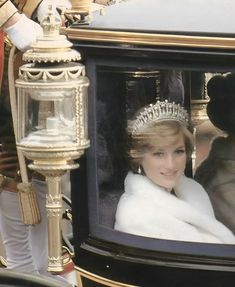 a woman in a tiara is looking out the window of a horse drawn carriage