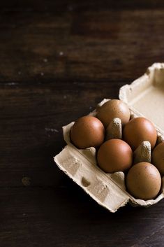 an egg carton filled with brown eggs on top of a wooden table