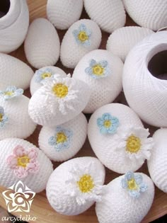 white crocheted eggs with flowers on them are sitting in a bowl next to yarn