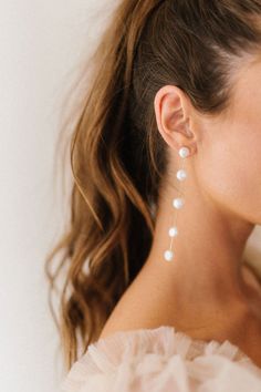 a woman wearing earrings with pearls on them