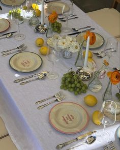 the table is set with silverware, plates and fruit for an elegant dinner party