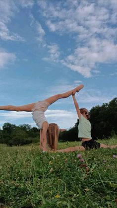 two women doing yoga in a field under a blue sky