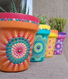 colorful painted pots with succulents and cacti on the side of a building