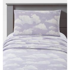 a bed with purple and white clouds on the comforter, pillows and pillow cases