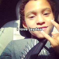 a young boy sitting in the back seat of a car making a peace sign with his fingers