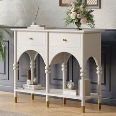 a white console table with gold legs and flowers on top