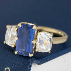 A JbyG trilogy ring with the most delicious sapphire we've come across in a while! That delicious royal blue velvety color in the center is irresistible, flanked by chunky, rustic elongated old mine cut diamonds. Together, they give you tons of color, sparkle, and spread across the top of one's finger. All set in yellow gold, this is one of our favorite original rings to come out of production as of late! 18kt yellow gold Size 6 and fully resizable Sapphire measures 9.87 x 5.53 x 3.75mm, heated Emerald Cut Sapphire Three Stone Jewelry, Gift Sapphire Three-stone Baguette Cut Ring, Baguette Cut Three Stone Sapphire Ring Gift, Gift Radiant Cut Three Stone Sapphire Ring, Modern Mens Rings, Diamond Trilogy Ring, Art Jewelry Earrings, Trilogy Ring, Antique Watches