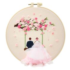 a bride and groom sitting on a swing in front of a cherry blossom tree with pink flowers