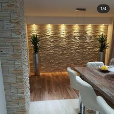 a dining room table with white chairs next to a wall made out of stone bricks