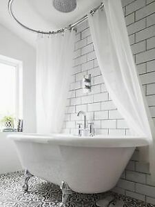 a white bath tub sitting under a window next to a tiled floor with black and white tiles