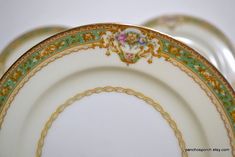 three plates are stacked on top of each other with gold trimmings and floral designs