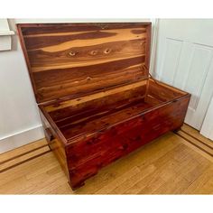 an empty wooden box sitting on top of a hard wood floor next to a door