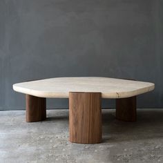 a table made out of wood and concrete with two legs on each side, in front of a gray wall