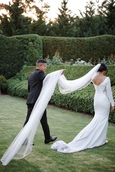 a man and woman standing in the grass with a veil over their heads as they look at each other