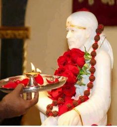 a person holding a plate with flowers on it and a statue in the back ground