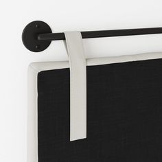 a black and white headboard hanging on the wall next to a curtain with a tie