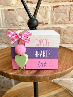 a wooden block with candy hearts on it sitting on a table next to a brick wall