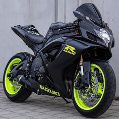 a black and yellow motorcycle parked next to a wall