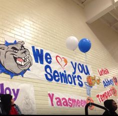 there are many signs on the wall in this school gym that say, we love you seniors