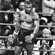 a black and white photo of a man standing in the middle of a boxing ring