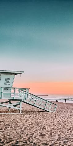 a lifeguard station on the beach at sunset