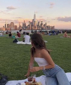 a woman sitting on top of a grass covered field next to a plate of food