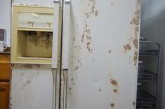 an old refrigerator with the door open and rusted on it's side in a kitchen