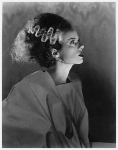 a black and white photo of a woman with curly hair in an old fashion hairstyle