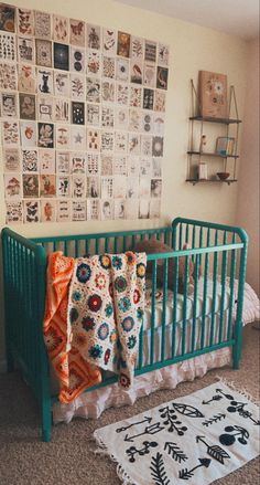 a baby crib in front of a wall with pictures on it and a rug