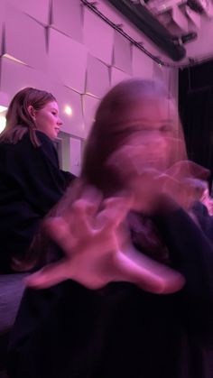 two women are standing in front of a mirror and one is holding another woman's hair