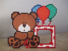 a brown teddy bear sitting on top of a table next to balloons and a camera